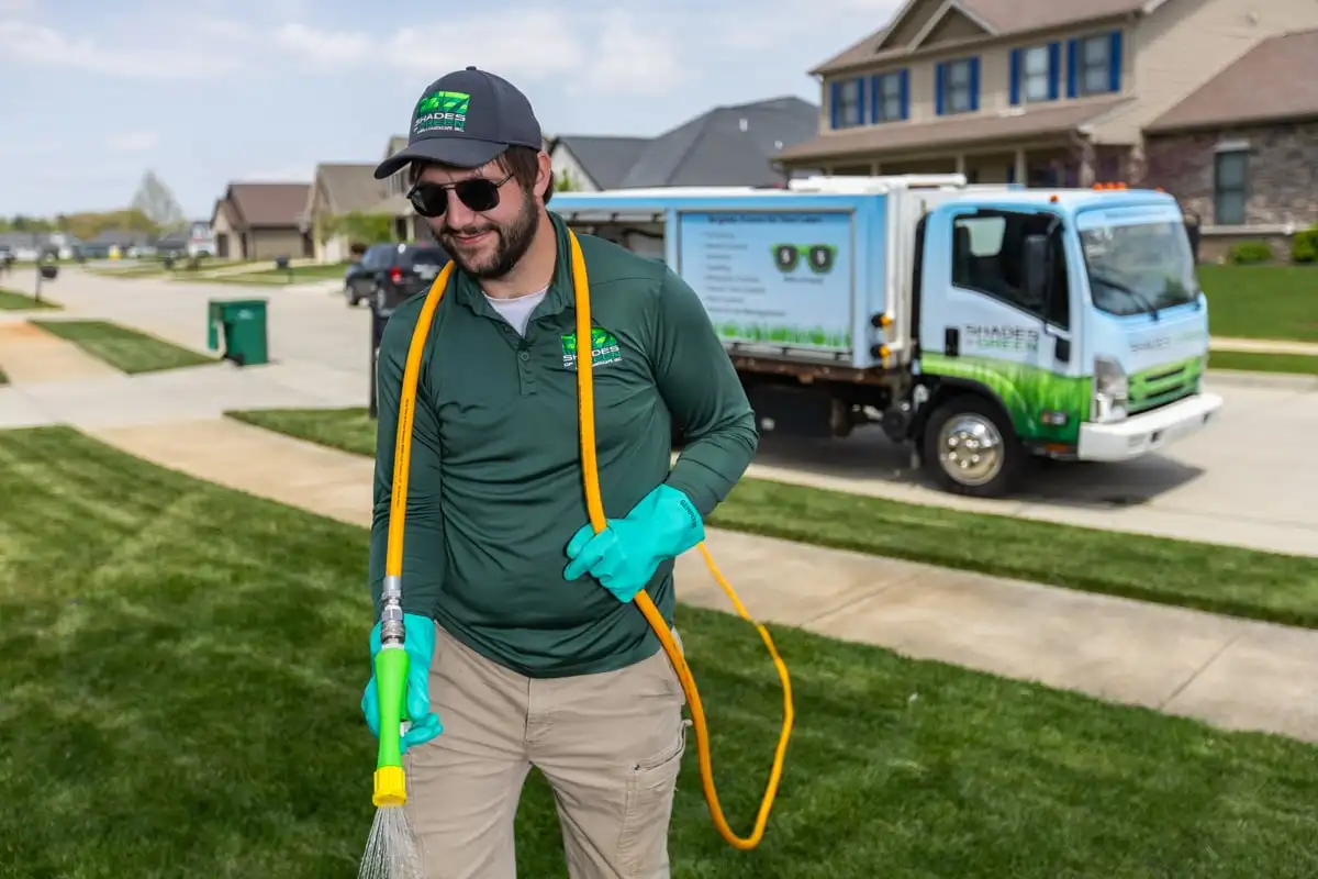 Shades of Green technician applying a liquid lawn treatment with a hose