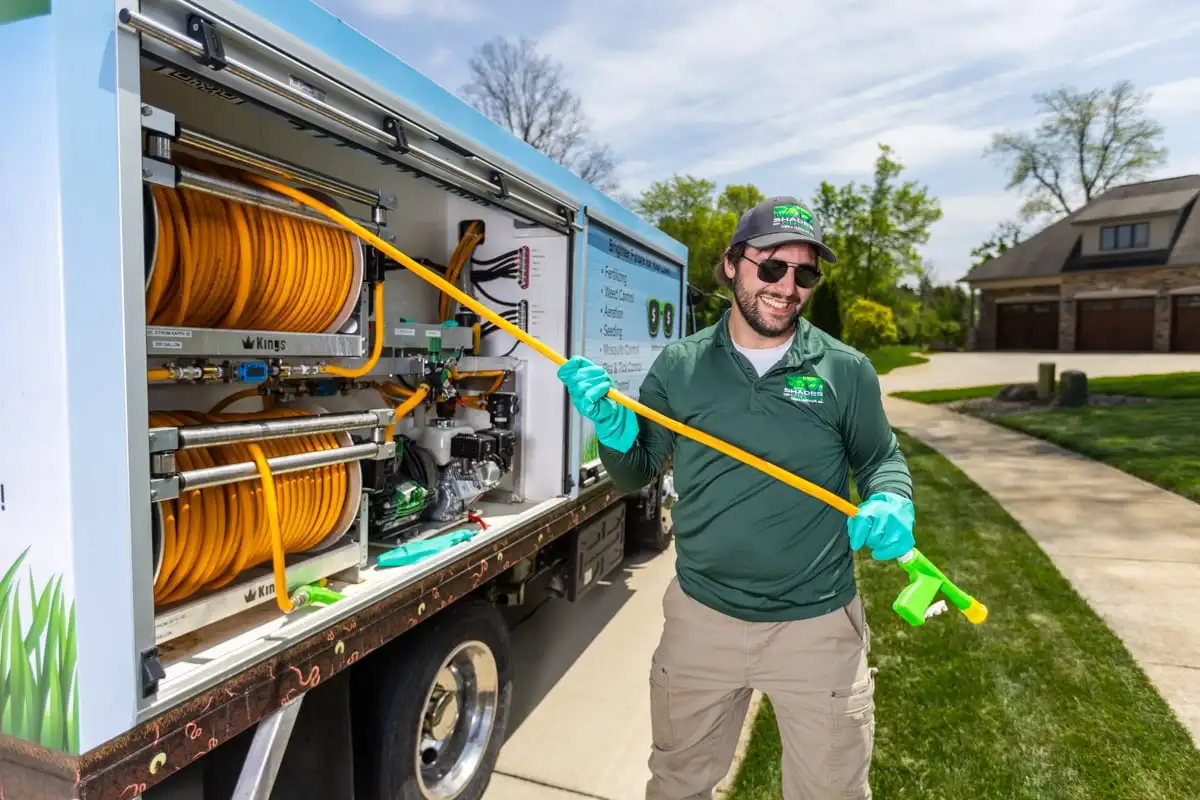Smiling technician handling a treatment hose beside a service truck