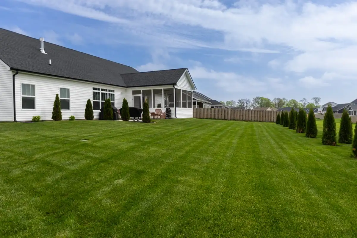 Green backyard lawn beside a white home