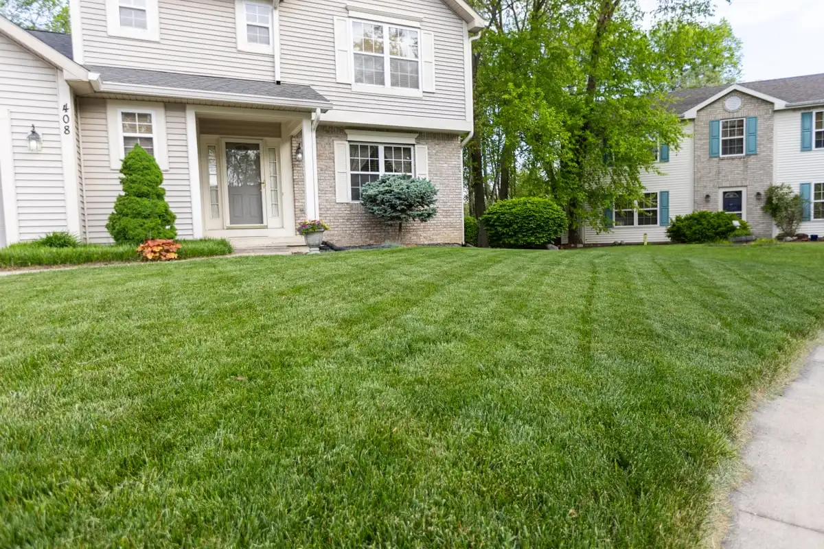 Green front lawn beside a driveway and two-story home