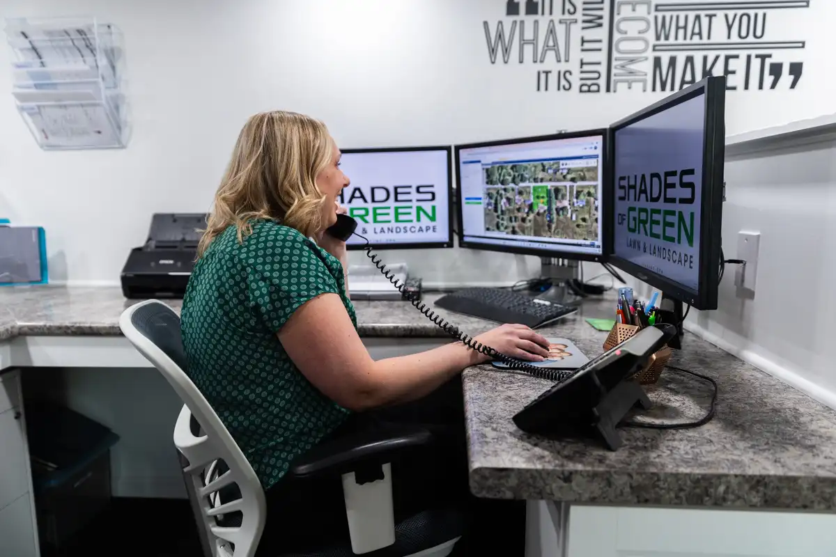 Customer service rep on a call at a three-monitor desk in the Shades of Green office