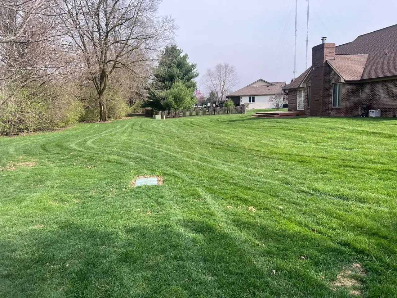 Green backyard lawn beside a brick home in Kokomo, Indiana