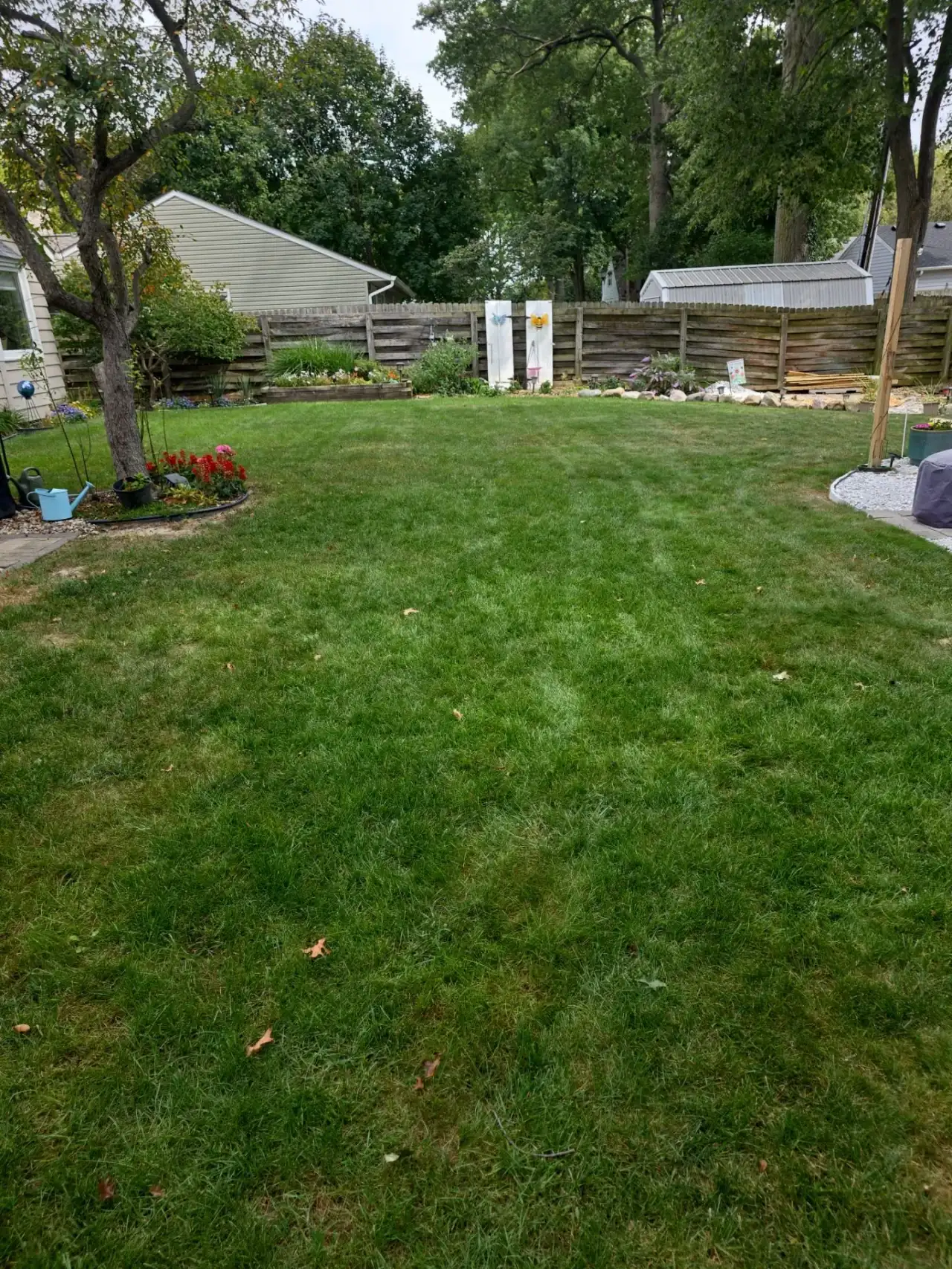 Backyard lawn with flower beds and a wooden fence in Lafayette, Indiana