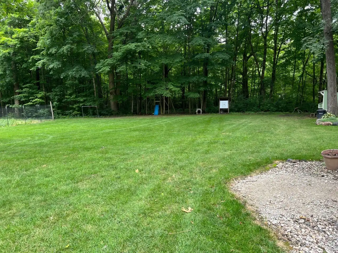 Backyard lawn bordered by tall woods in Battle Ground, Indiana
