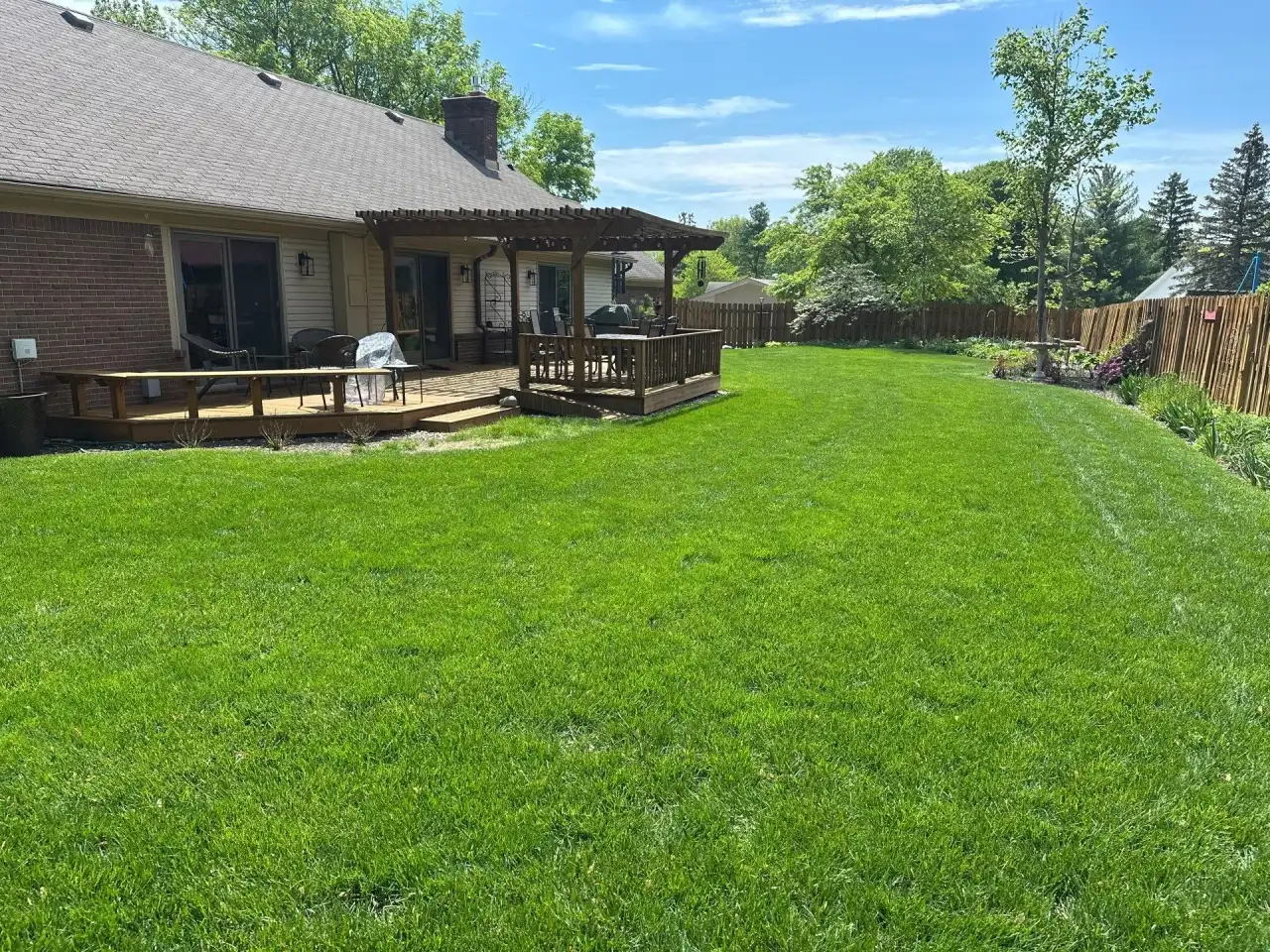 Green backyard lawn beside a wooden deck in Lafayette, Indiana