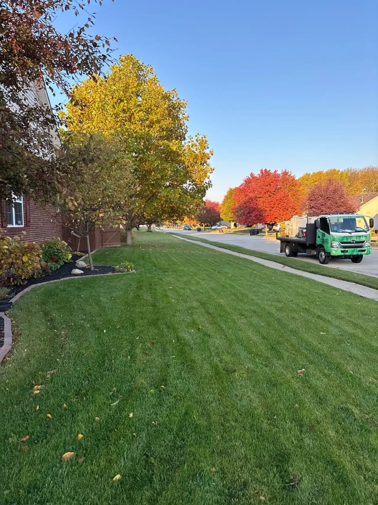 Shades of Green service truck on a tree-lined Lafayette, Indiana street in fall