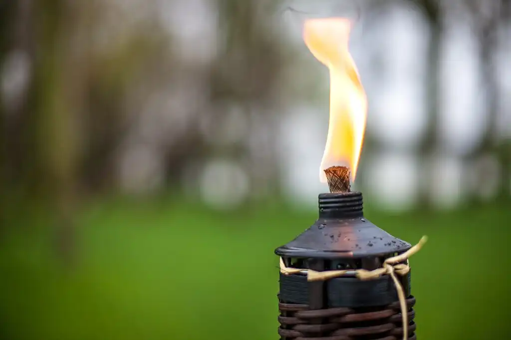 Lit tiki torch burning in a backyard