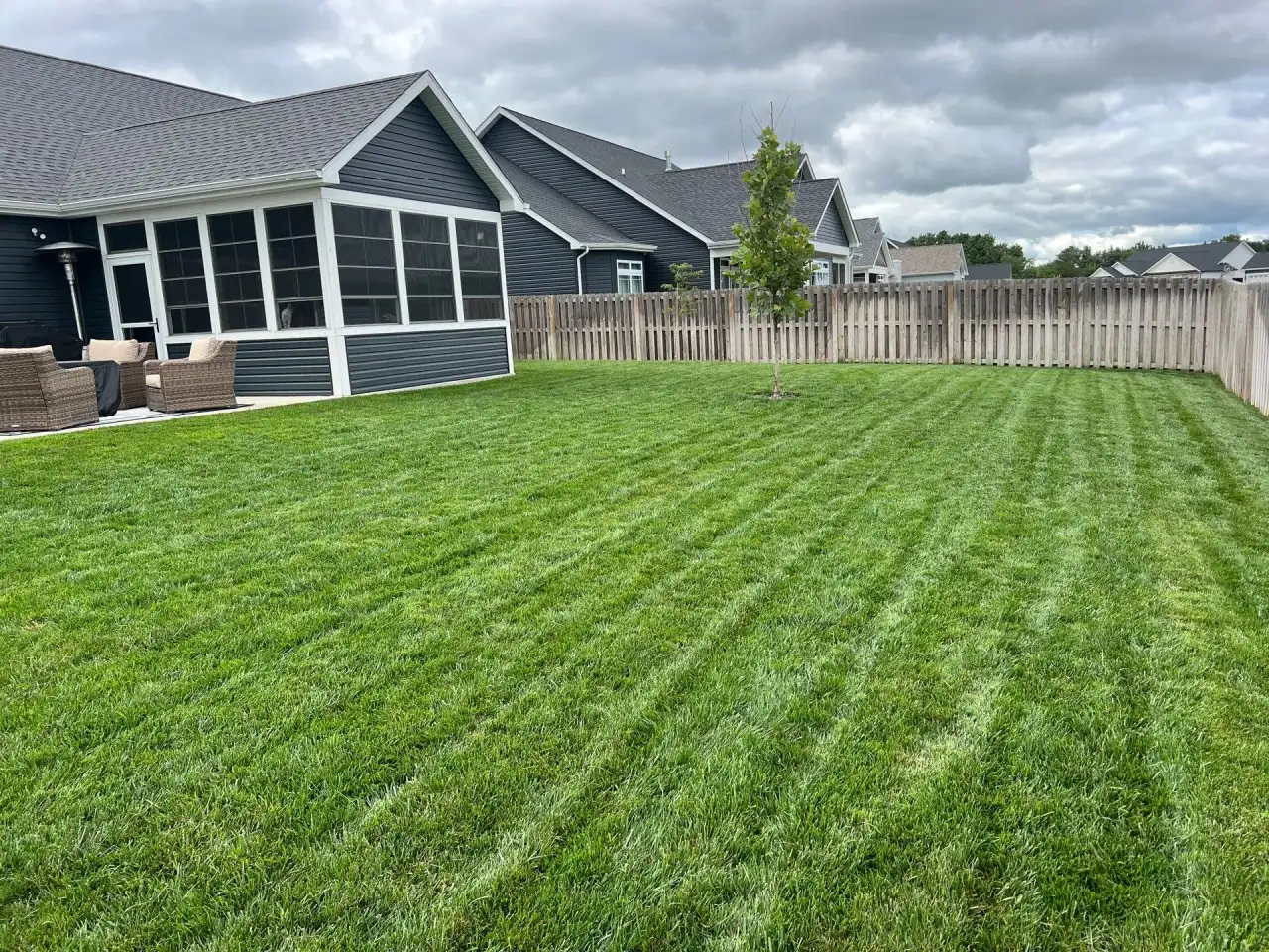 Striped backyard lawn behind a Lafayette, Indiana home with a screened porch