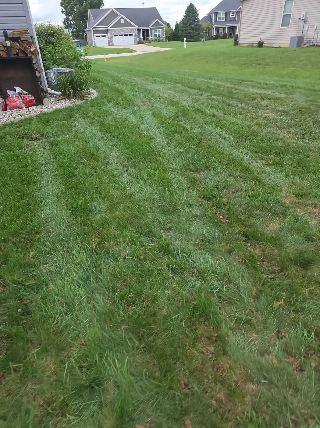 Striped lawn sloping toward neighboring homes in Battle Ground, Indiana