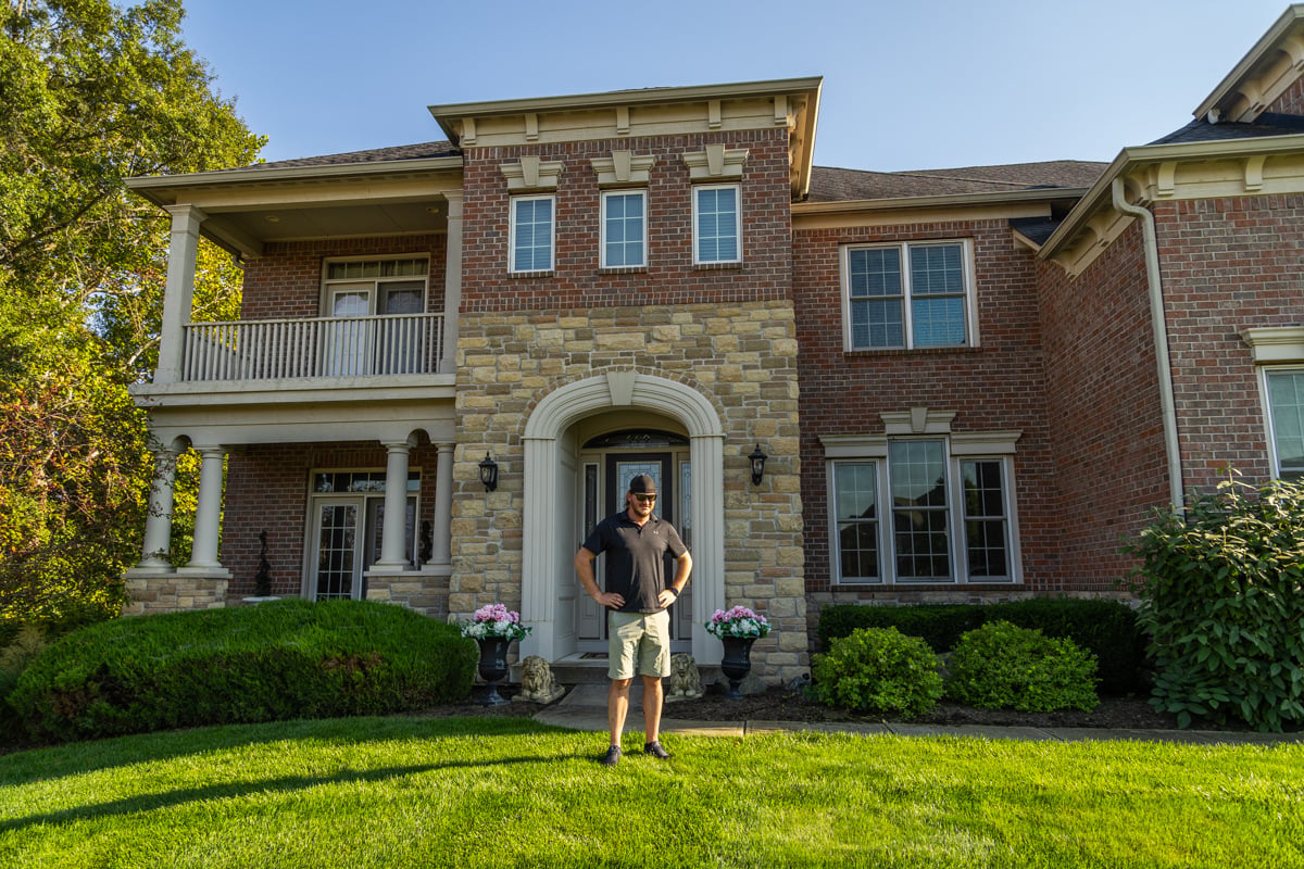 a proud homeowner stands in his well-manicured grass