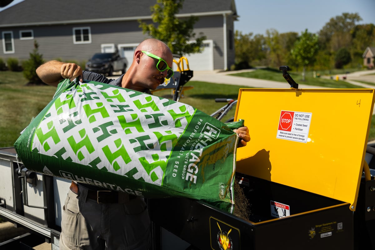 lawn care technician loading the best grass seed into a hopper