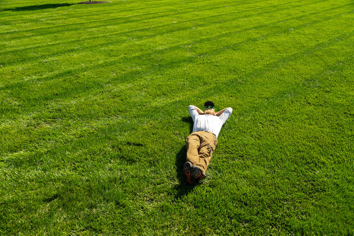 happy person laying in their green grass