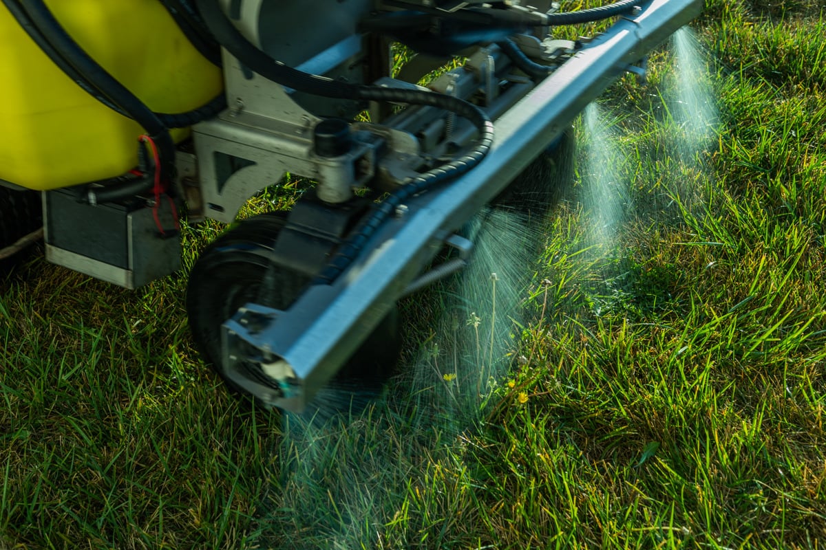 a close up of quick-release liquid fertilizer being sprayed onto grass out of a machine