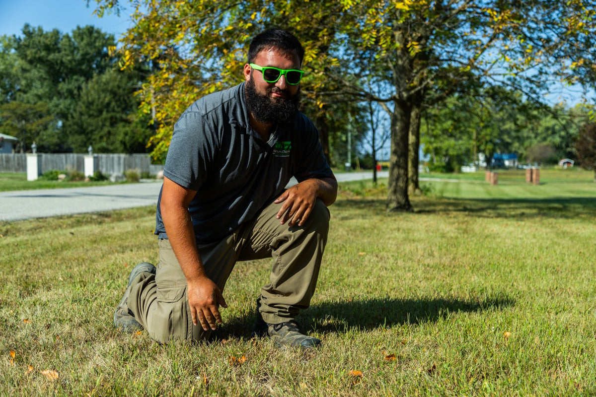 lawn tech inspecting a struggling lawn that had a bad lawn care schedule