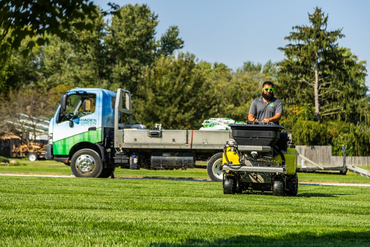 lawn care technician applying a treatment at the best time to fertilize