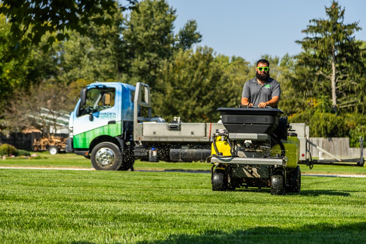 lawn tech applying a granular fertilizer treatment