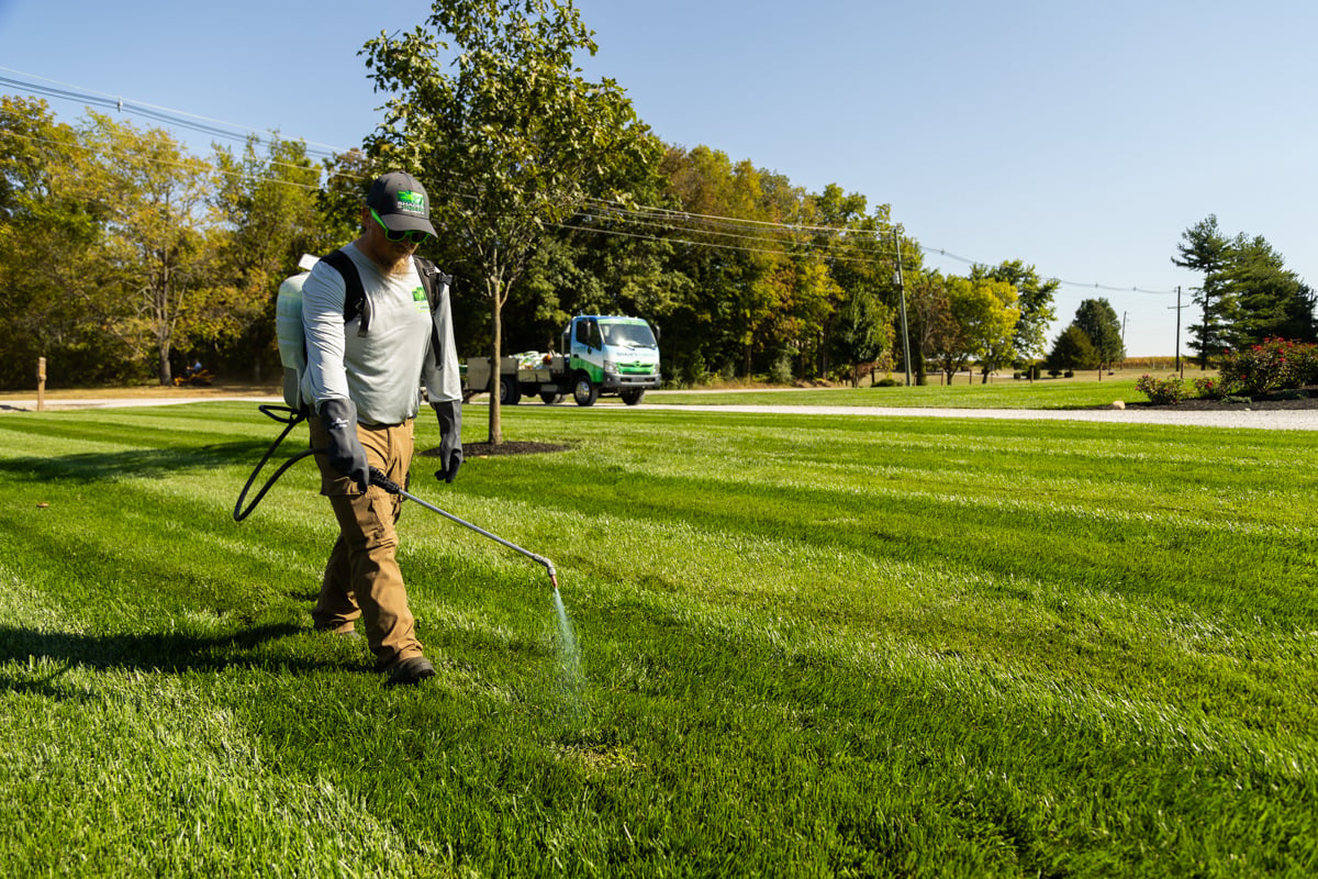 lawn care tech spraying weed control by hand