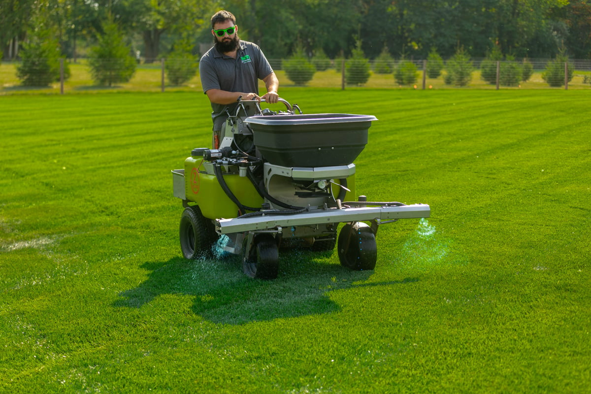 lawn care technician applying liquid weed control product